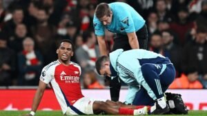 Arsenal player Jurrien Timber sitting on the floor while being attended to by medics