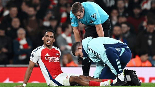 Arsenal player Jurrien Timber sitting on the floor while being attended to by medics