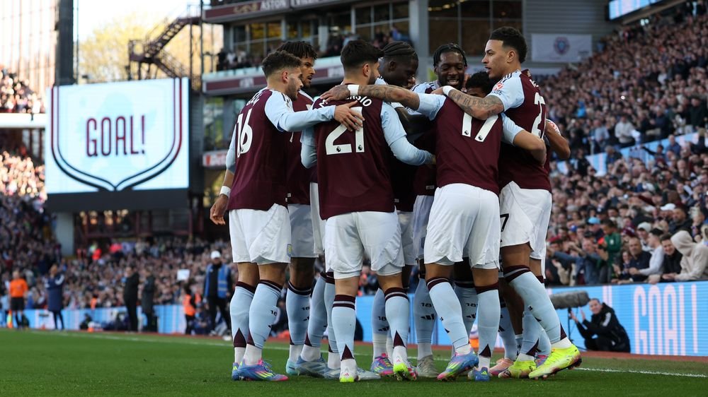 Aston Villa squad huddled together on the pitch at night