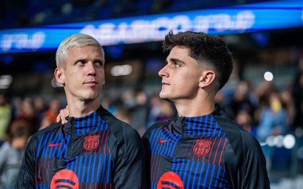 Barcelona stars Pau Victor and Dani Olmo standing in a stadium in their kits