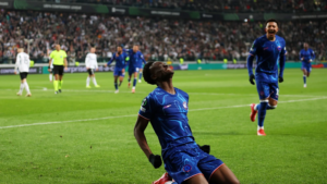 Chelsea player Tyrique George sliding in celebration in stadium at night