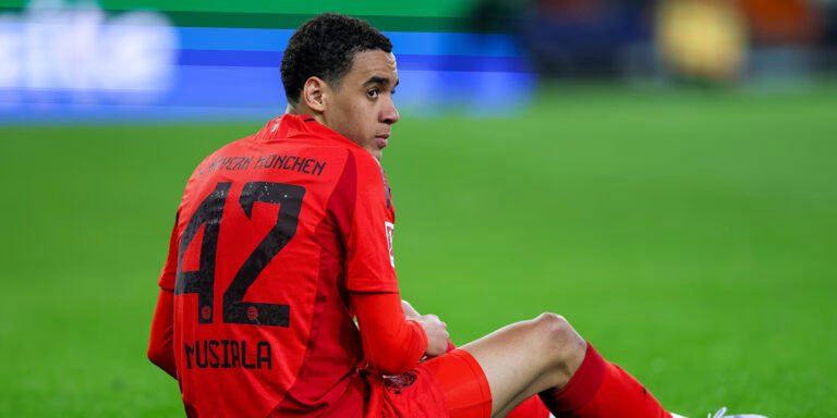 Bayern midfielder Jamal Musiala sitting on the pitch after sustaining an injury