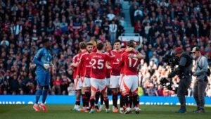 Manchester United squad clapping and hugging each other in stadium at night