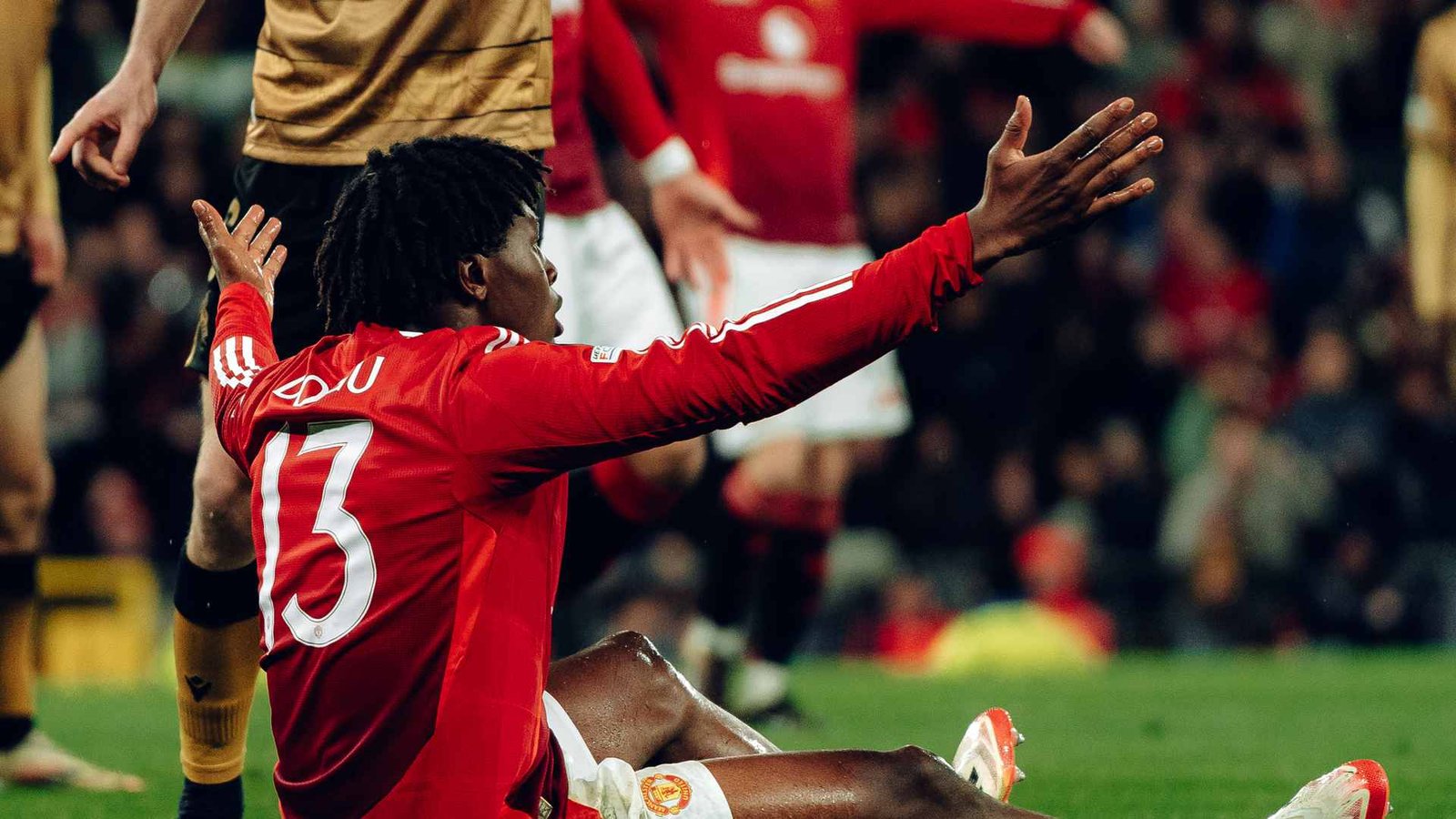 Manchester United wingback Patrick Dorgu sitting on the turf in a Europa League game