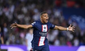 Kylian Mbappe wearing PSG colours and celebrating a goal in a stadium