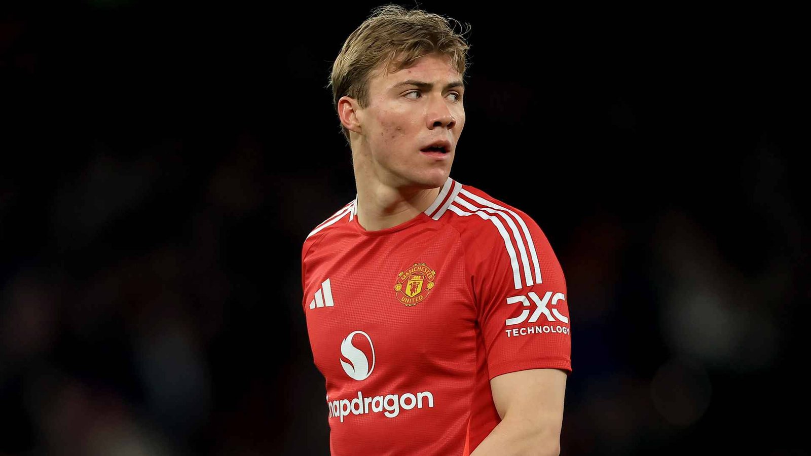 Manchester United forward Rasmus Hojlund walking against a dark background