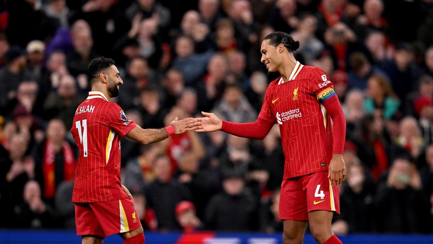 Salah and van dijk shaking hands at Anfield stadium at night time