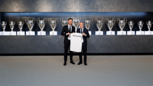 Xabi Alonso and Real Madrid president holding a Madrid shirt in front of trophies won by the club