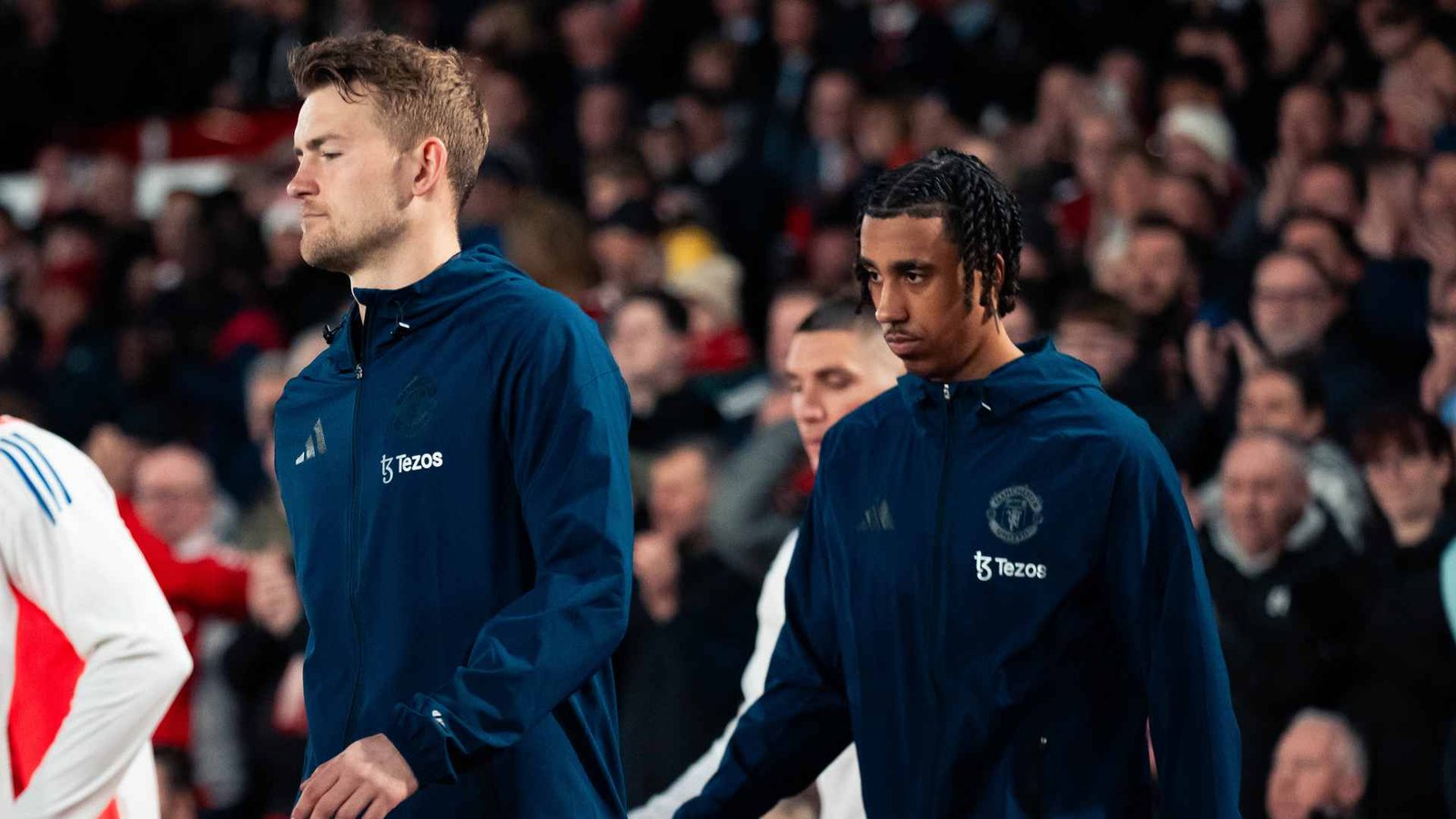 Manchester United defenders Leny Yoro and Mathijs de Ligt walking on the pitch