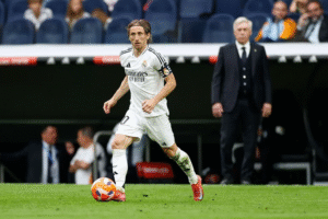 Real Madrid player Luka Modric on the ball as Carlo Ancelotti watches on from the sidelines