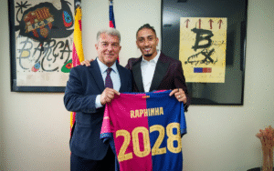 Raphinha holding up a Barcelona shirt with club president Laporta