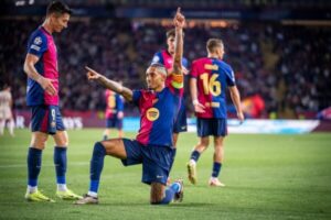 Barcelona forward Raphinha kneeling in celebration in a stadium