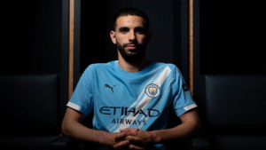 Rayan Ait-Nouri posing in Manchester City shirt with dark background