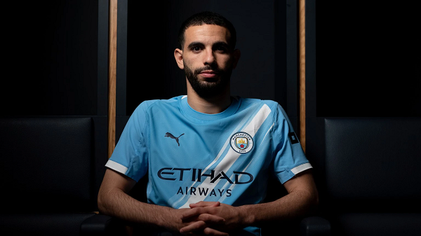 Rayan Ait-Nouri posing in Manchester City shirt with dark background
