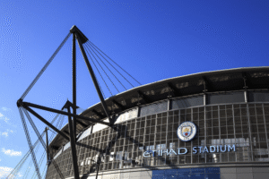 View of the Etihad Stadium, home of Manchester City, with the logo visible in the foreground