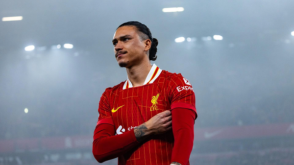 Darwin Nunez in a Liverpool shirt walking under floodlights at Anfield at nighttime