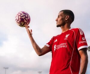 Alexander Isak posing in a Liverpool shirt at the club's AXA training centre