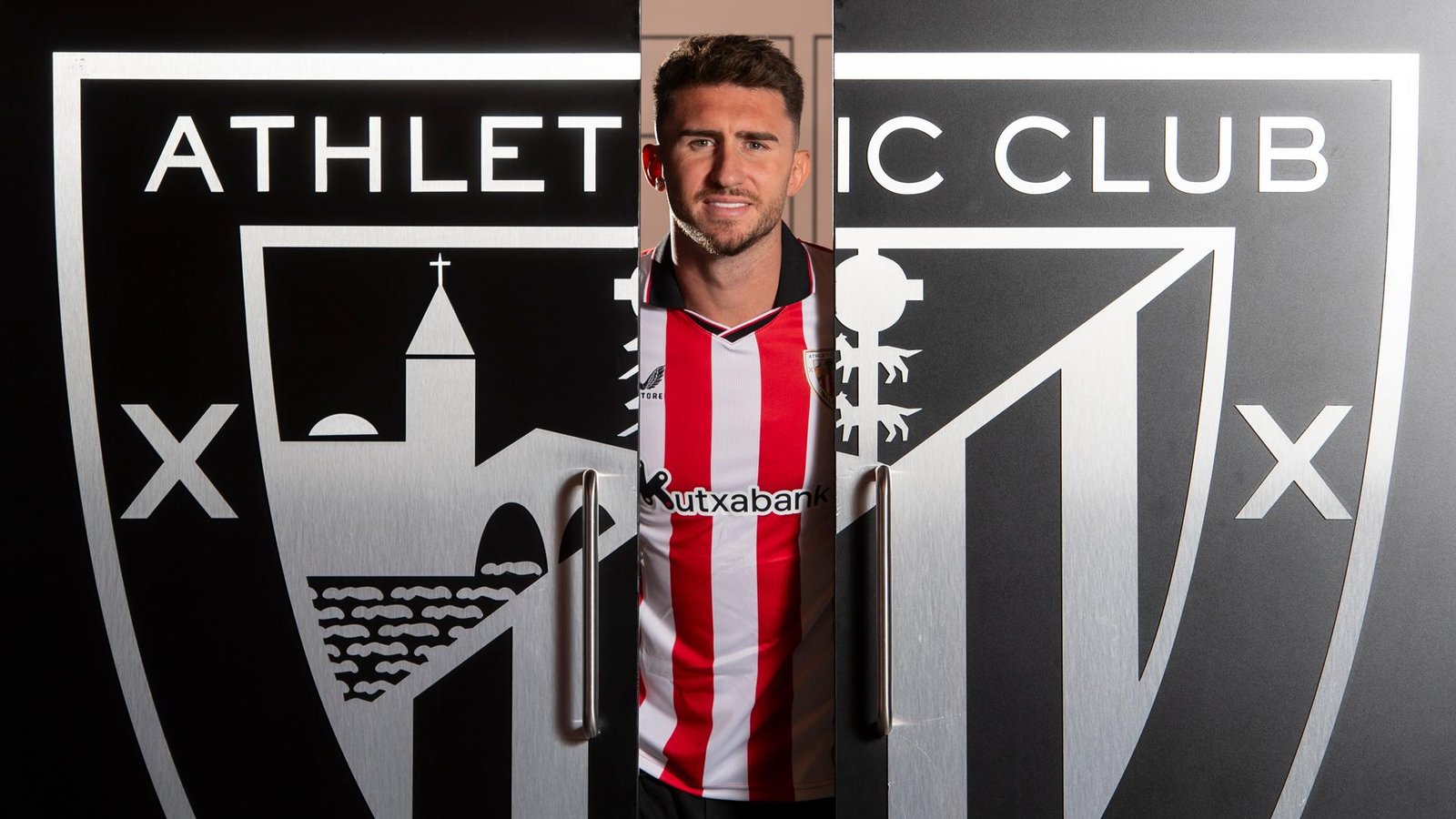 Aymeric Laporte posing in-between an Athletic Club badge built like a door