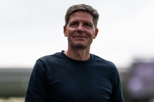 Oliver Glasner in a black t-shirt standing against the grey sky