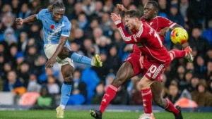 Manchester City's Jeremy Doku shooting the ball while two Liverpool players try to block