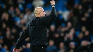 Pep Guardiola raising his fist to acknowledge fans at the Etihad