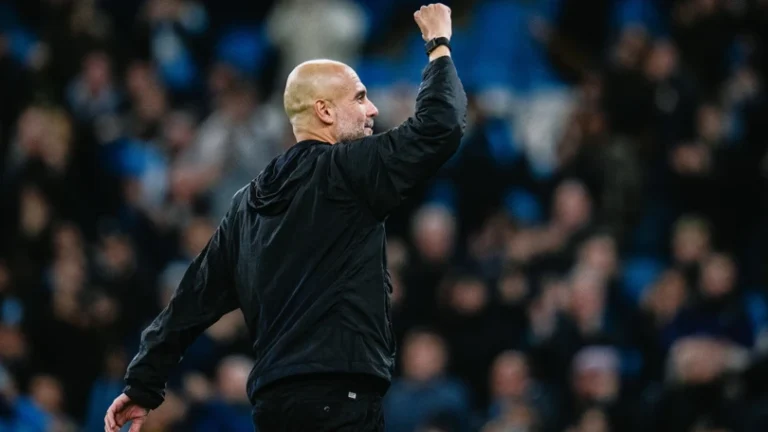 Pep Guardiola raising his fist to acknowledge fans at the Etihad