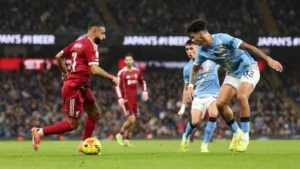 Liverpool forward Mohamed Salah attempting to evade Manchester City's Nico O'Reilly.