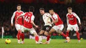 Arsenal players surrounding Liverpool's Alexis Mac Alliser