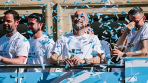 Pep Guardiola celebrating with beer and confetti during Manchester City's open-top bus parade