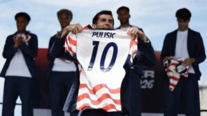 USA player Christian Pulisic holding up his football jersey