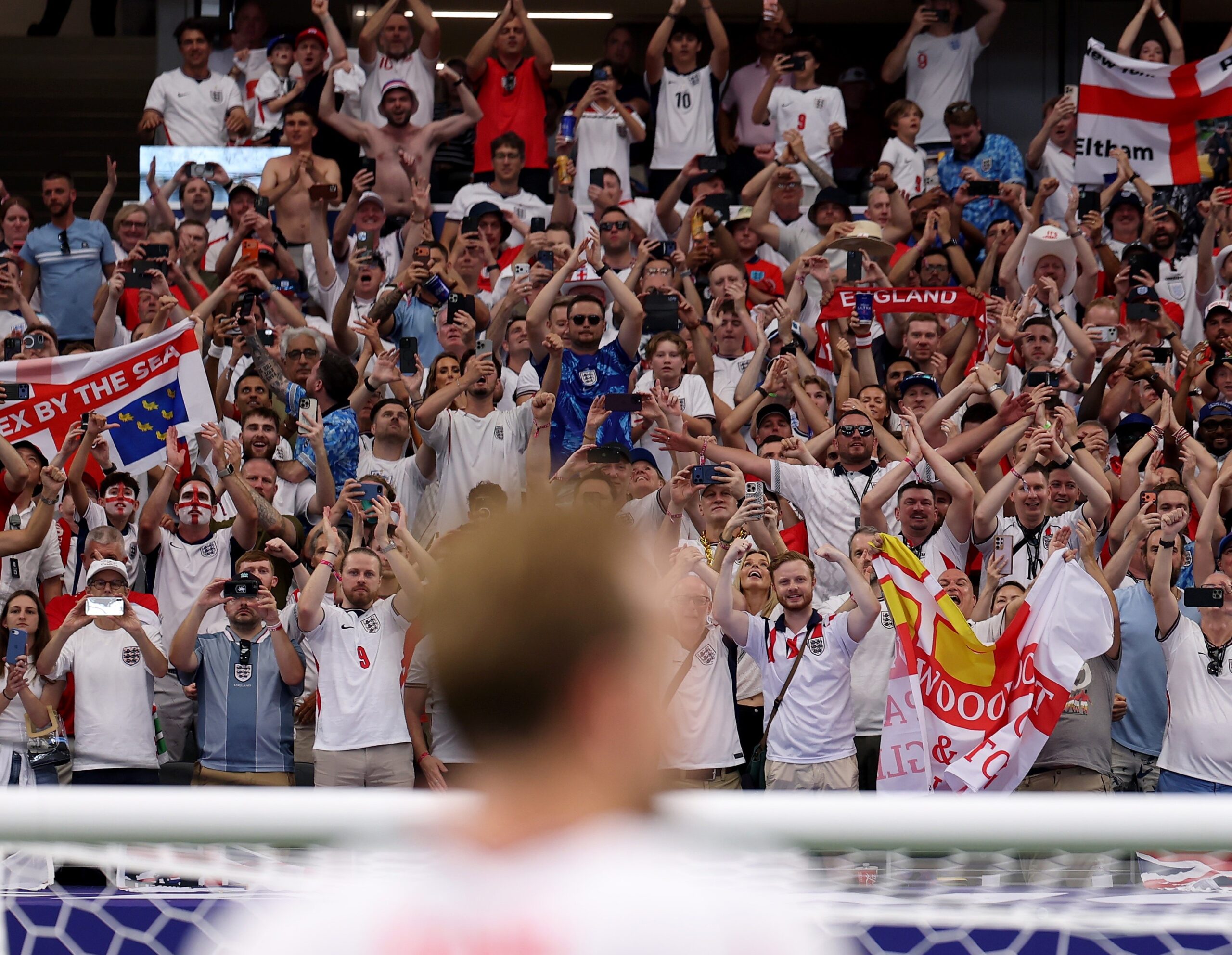 England fans celebrating at World Cup, with Harry Kane blurred in the foreground
