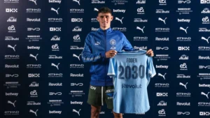 Phil Foden holding up a Manchester City shirt after signing new contract