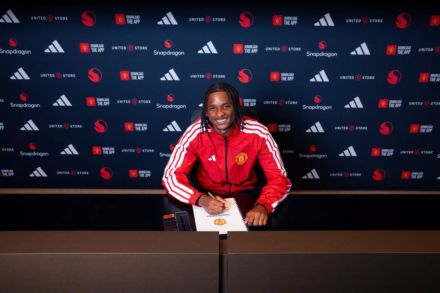 Tynan Thompson posing as he signs a Manchester United contract