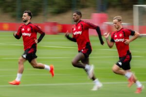 Manchester United captaining Bruno Fernandes running on the training ground alongside Marcus Rashford and another teammate