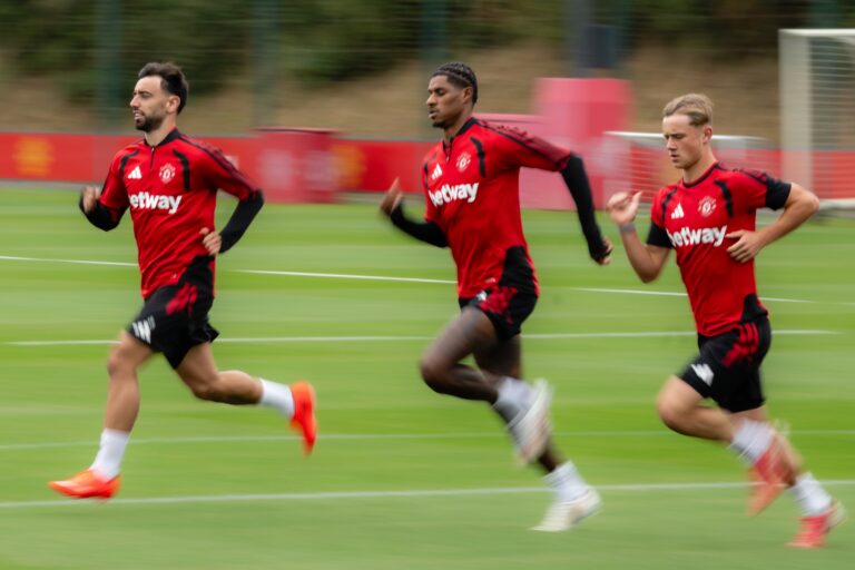 Manchester United captaining Bruno Fernandes running on the training ground alongside Marcus Rashford and another teammate
